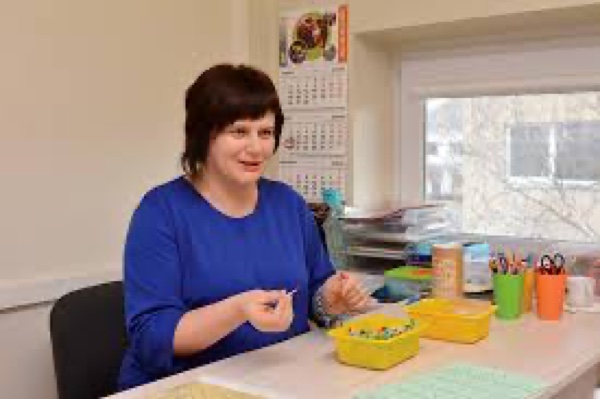 Logopedė Diana dirba prie stalo su mokymo priemonėmis